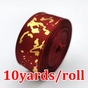Vista dettagliata del rotolo di nastro in raso rosso scuro con motivo marmo dorato, 2,5 cm.