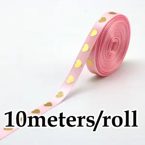 Primo piano dettaglio nastro di raso rosa con cuori dorati, 10 metri per rotolo confezione.