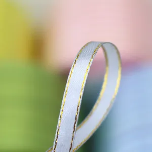 Close-up detail shot of white satin ribbon with gold edge trim, perfect for gift wrapping and bow.