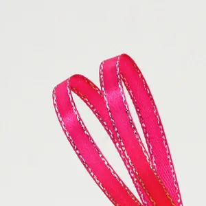Close-up detail of bright pink satin ribbon with shimmering silver metallic edge trim.