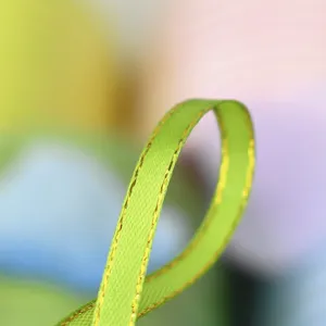 Close-up detail of green ribbon with golden edge, delicate woven texture and shiny border.