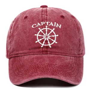 Detailed close-up showing white Captain embroidery and ship wheel on a red washed cotton cap