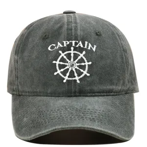 Macro view of white Captain embroidery and nautical wheel on washed grey baseball cap
