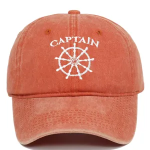 Detail of white Captain embroidery and ship wheel on a washed orange baseball cap