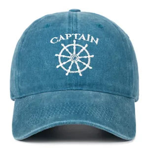 Detail view of washed denim baseball cap featuring white Captain embroidery and wheel.