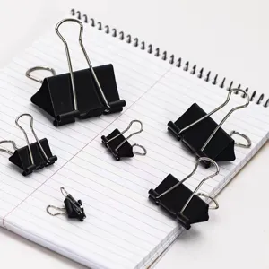 Primo piano dettagliato di clip per raccoglitori in metallo nero assortite su carta a righe.
