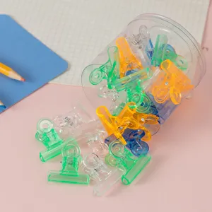 Transparent colorful small binder clips set in a clear container for stationery and desk organization.
