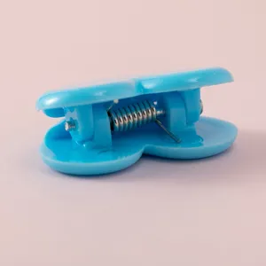 Dettaglio in primo piano di una clip in plastica azzurra a forma di cuore con molla.