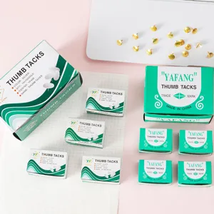 Detailansicht von grün verpackten Pinnnadeln und verstreuten goldenen Reißzwecken.