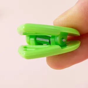Vista ravvicinata di una mini clip in plastica verde brillante con molla metallica per uso quotidiano.
