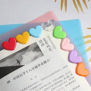 Dettaglio di graffette colorate a forma di cuore, perfette per organizzare foto e sacchetti.