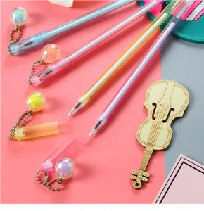 Close-up detail showing colorful pastel gel pens with faceted crystal ball pendants on desk