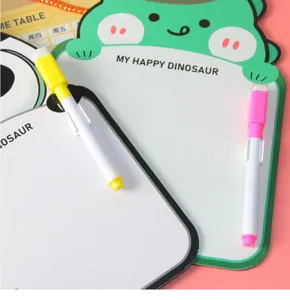 Close-up detail of a cute green cartoon dinosaur erasable drawing board with two markers