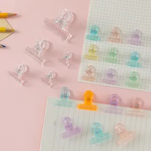 Close up detail of colorful transparent binder clips arranged on memo pads for office use.