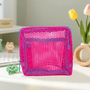Detailed view of bright pink mesh cosmetic bag with blue zipper, cute desktop style.