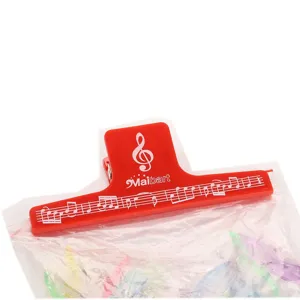 Close-up detail of red plastic music clip with musical notes design for secure binding.