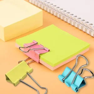 Detailed close-up of colorful binder clips on sticky notes, perfect for office organizing.