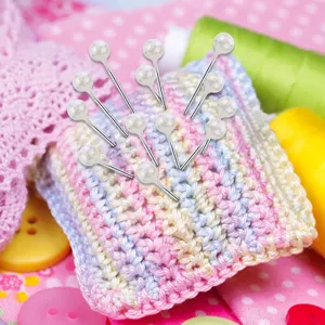 Close-up detail of colorful pearl head sewing pins set on a knitted cushion for crafting.