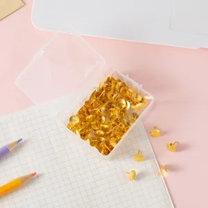 Gold metal pushpins in clear plastic storage box, ideal for office bulletin board and home wall art deco.