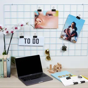 Detailed view of black binder clips and paper clips organizing notes on a metal wire grid wall.
