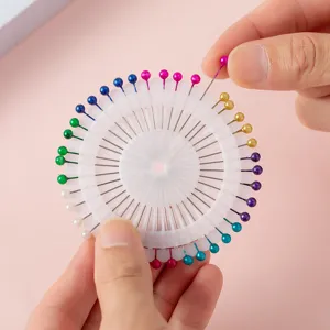 Detailed close up of colorful pearl head sewing pins in white round storage wheel.