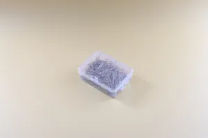 Close-up detail of silver straight pins in a clear storage box for sewing and office use.