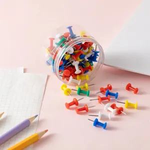Punaises en plastique colorées dans un pot transparent, idéales pour le bureau et tableaux.
