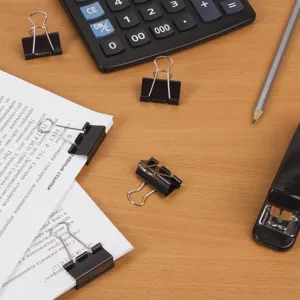 Close-up view of black metal binder clips organizing documents on a tidy wooden office desk.