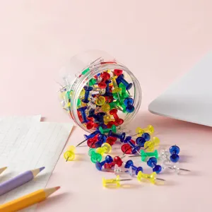 Punaises en plastique colorees dans un conteneur cylindrique transparent pour bureau.