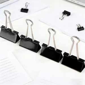 Close-up detail shot of black metal binder clips arranged neatly on clean white paper.