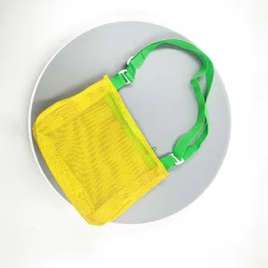 Close-up detail of the yellow mesh beach bag with green strap, showcasing the fabric and strap.