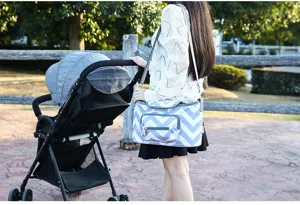 Outdoor lifestyle detail shot of a grey and white chevron baby diaper bag and stroller organizer.