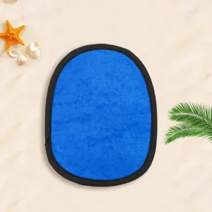 Detail shot of the blue sand removal mitt with black edge, resting on beach background.