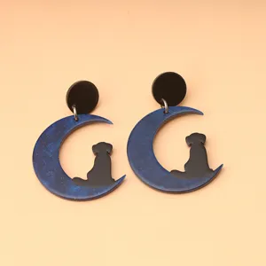 Vista detallada de pendientes colgantes de acrílico con luna y gato con brillo azul.