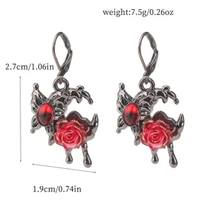 Nahaufnahme von gotischen Ohrringen aus schwarzem Metall mit rotem Kristall und Rosen-Design.
