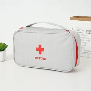 Détail de sac de premiers secours gris portable, avec broderie croix rouge et tissu résistant.
