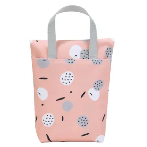 Pink waterproof diaper storage bag with cute abstract dot pattern and durable gray handles for baby.