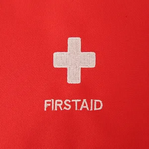 Gros plan détail du tissu de sac de premiers secours rouge avec broderie croix blanche.