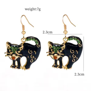 Detailed view of black cat rhinestone drop earrings, featuring gold-toned metal and green crystals.