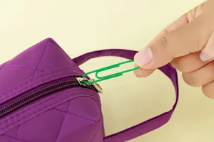 Close-up detail of large colorful paper clip used as creative zipper pull for storage bag.