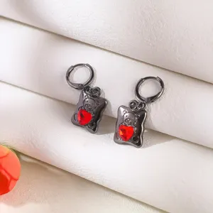 Detailaufnahme von dunklen Punk-Ohrringen aus schwarzem Metall mit Bärchen und rotem Herz-Kristall.