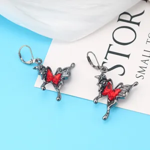 Nahaufnahme von dunklen gotischen Metall Schmetterlingsohrringen mit roten Kristallen.