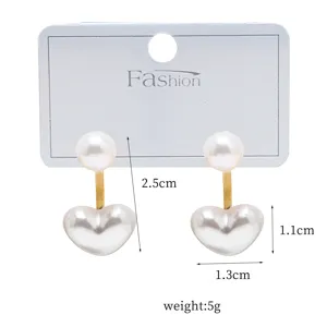 Detail view of double-sided pearl heart earrings with golden connecting rod, elegant design.