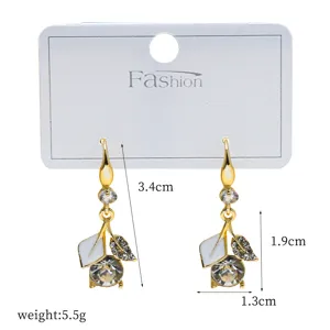 Gold-toned dangle earrings featuring white enamel leaves and sparkling rhinestones for women.