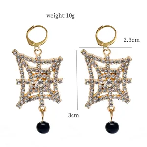 Detailed view of gold-tone rhinestone paved cross design drop earrings with dangling black beads.