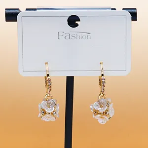 Exquisite gold hoop earrings featuring clustered white flower pendants with sparkling rhinestones.