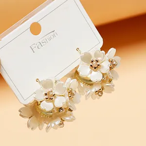 Chic white floral cluster earrings with sparkling rhinestone centers and gold tone base details.