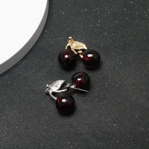 Détail de broche cerise exquise, tiges dorées et argentées avec fruits simulés rouge foncé.