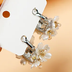 Elegant floral dangle earrings featuring white resin flower petals and sparkling crystal rhinestones.