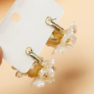 Elegant floral hoop earrings featuring white pearl petal design and sparkling rhinestone centers.